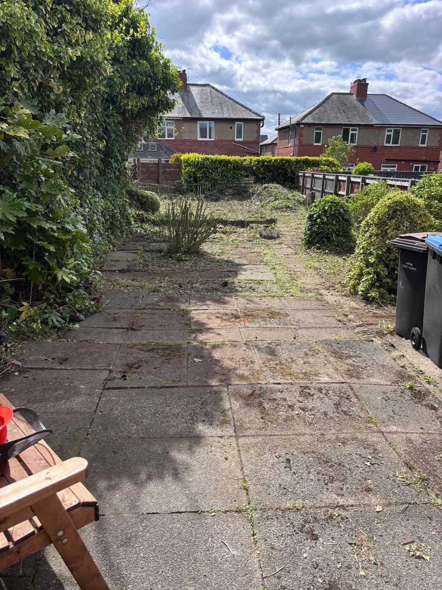 After: the same back garden cleared with the paving and paths showing again