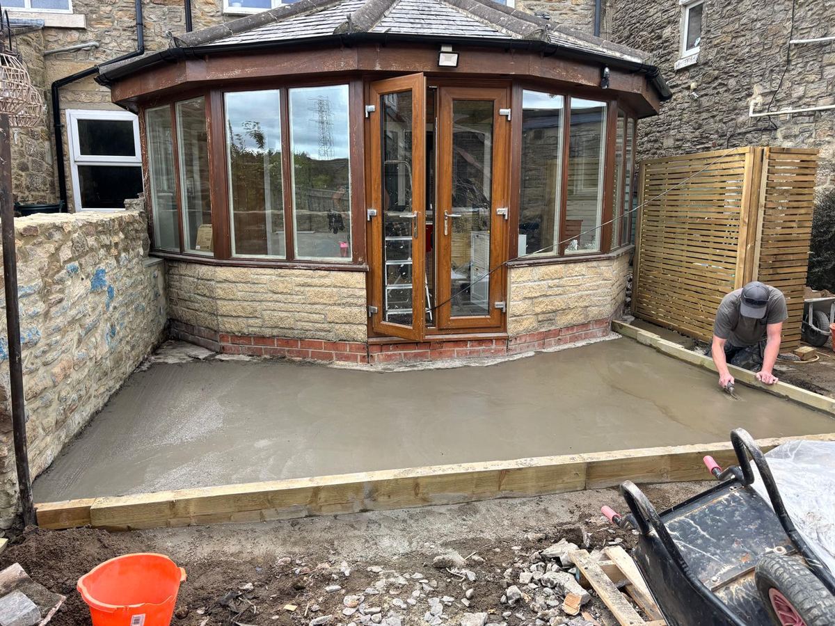 Before: fresh concrete base being levelled outside a conservatory